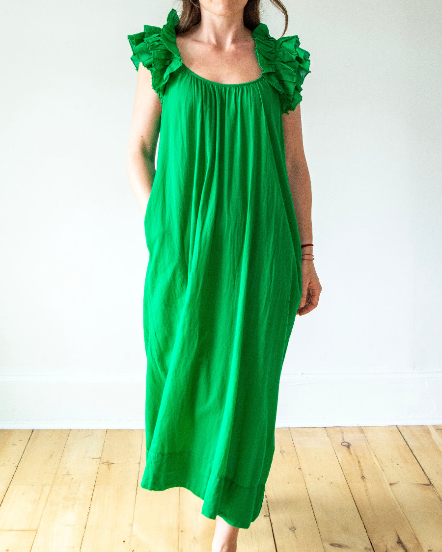 Person wearing a green dress with ruffled shoulders on a white background