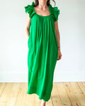 Person wearing a green dress with ruffled shoulders on a white background