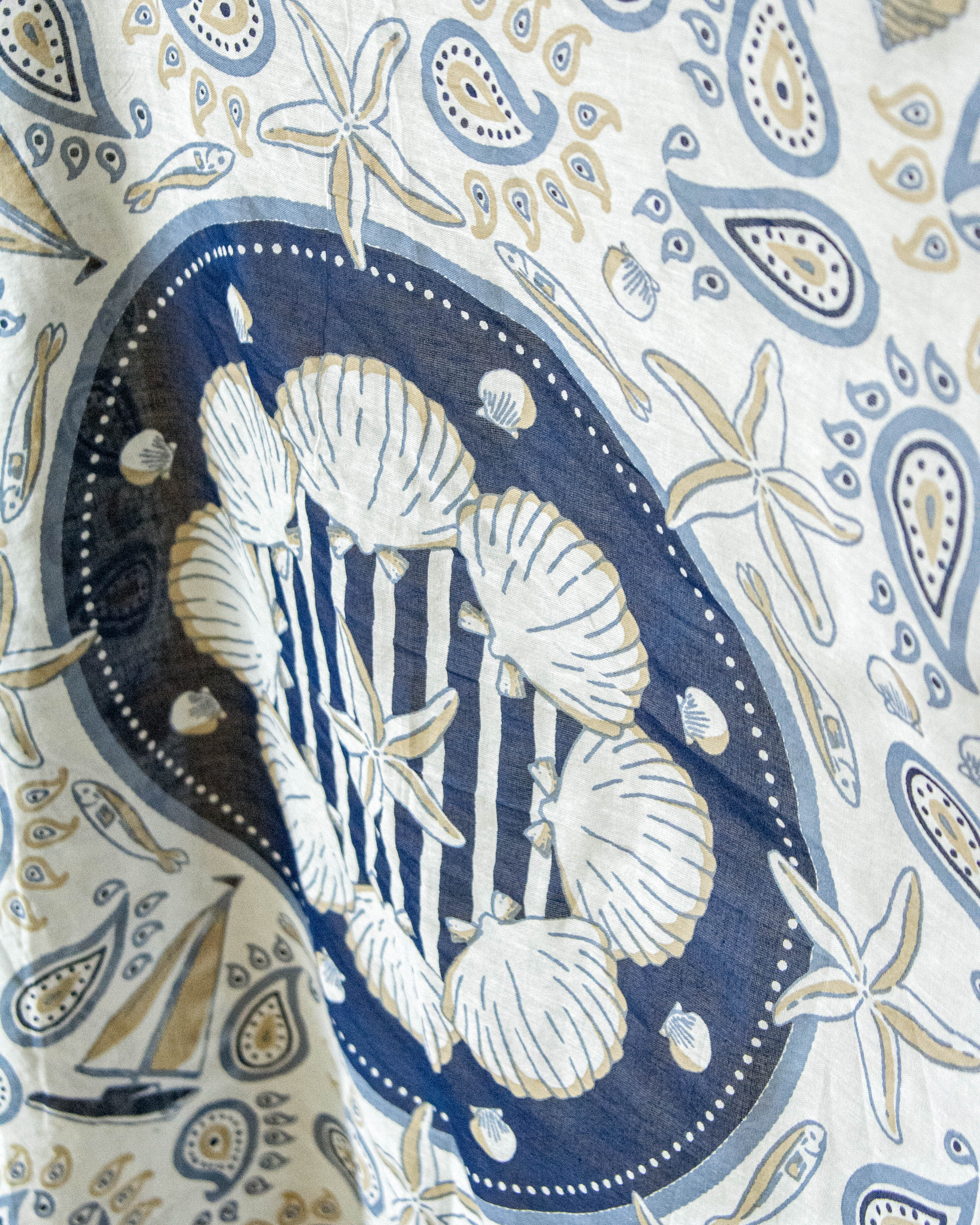 Patterned fabric with seashells and starfish design on a blue background